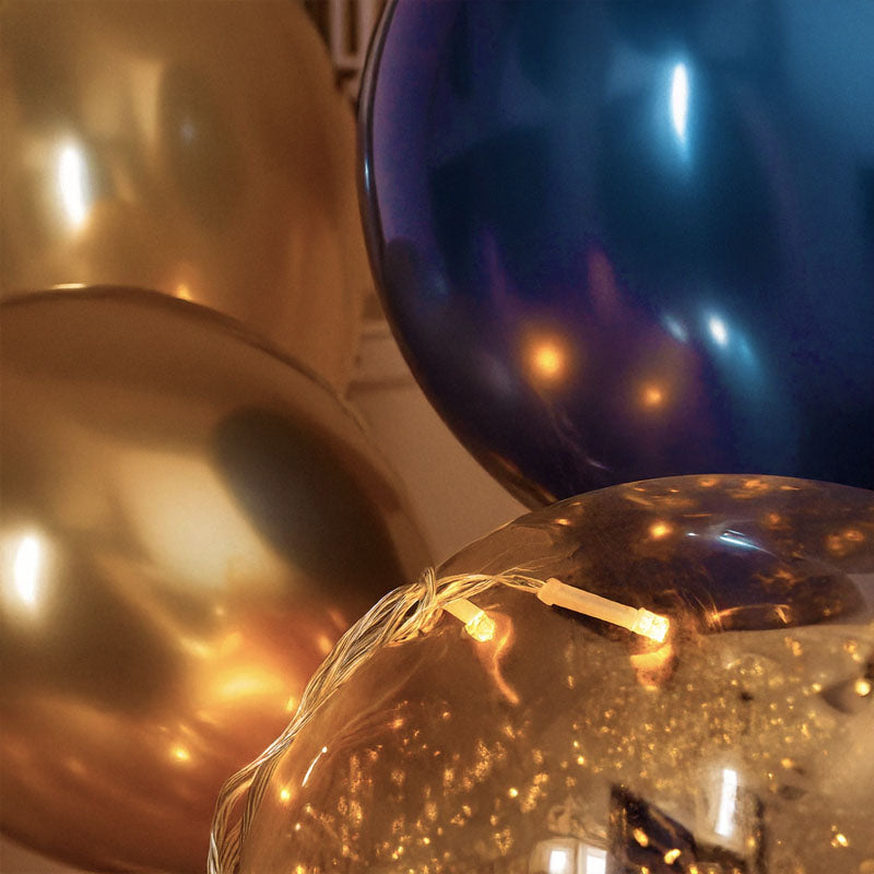 Close-up of reflective latex balloons with string lights.
