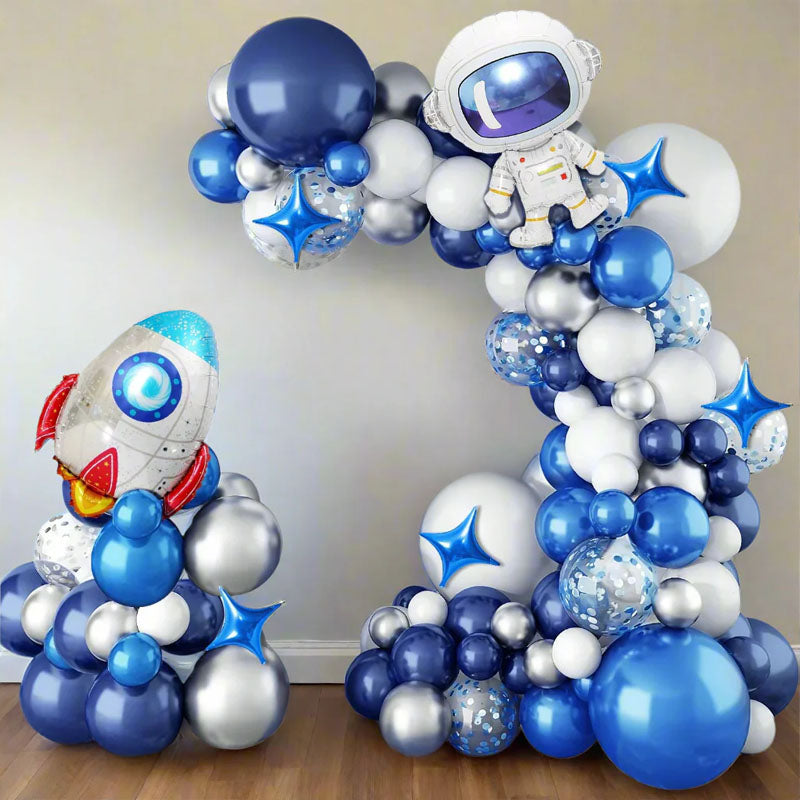 Balloon arch with astronaut and rocket design, featuring blue, white, and silver balloons.