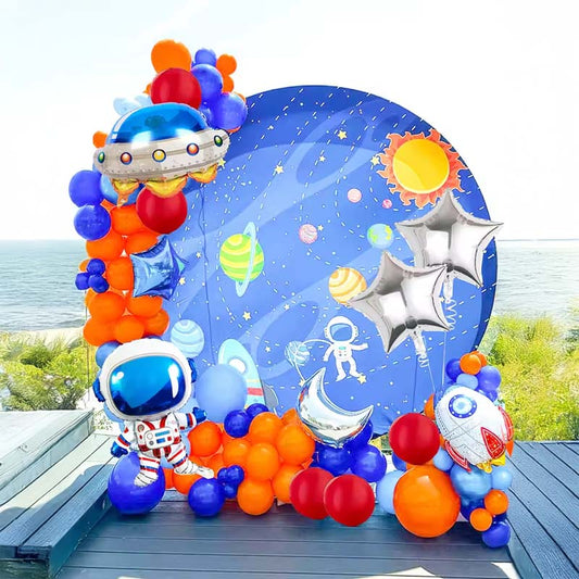 Colorful balloon arch with space-themed decorations on a wooden deck by the sea.