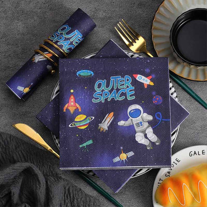Napkins with outer space design on a table setting with cutlery and plates.