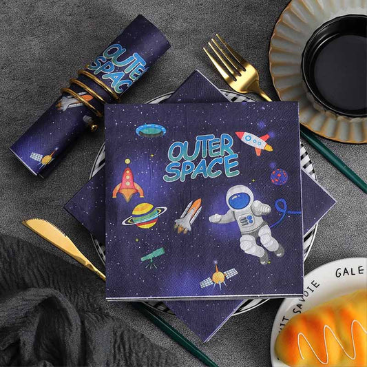 Napkins with outer space design on a table setting with cutlery and plates.